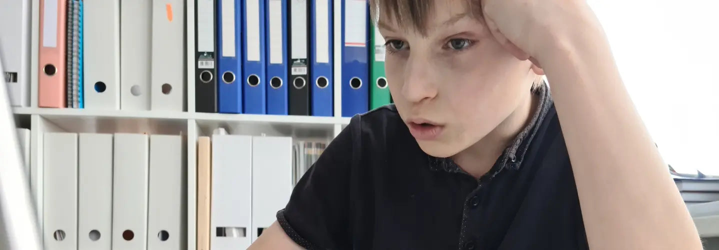 Child wearing violet Kids Hyperlight Eyewear while using a laptop for homework in a New Zealand home