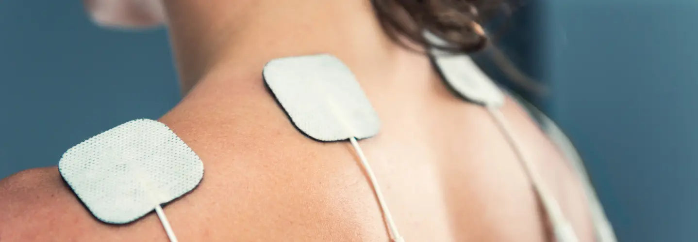 TENS unit with adhesive pads beside a handheld red-light and microcurrent device for a home pain tool comparison